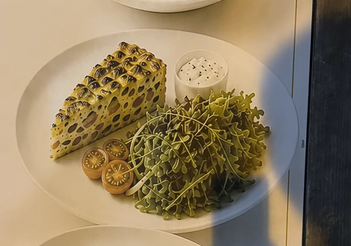 A menu photo of a quiche slice that looks like it's covered in mold